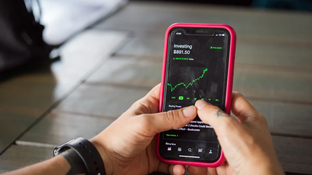 Crypto Trading for Beginners: Spot, Leverage, and Risk Basics Hands using phone with a rising trading chart