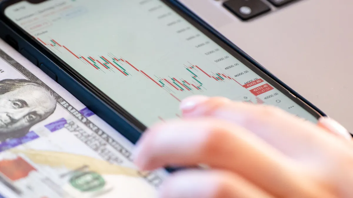 Crypto Trading for Beginners: Spot, Leverage, and Risk Basics Phone with market chart and cash nearby